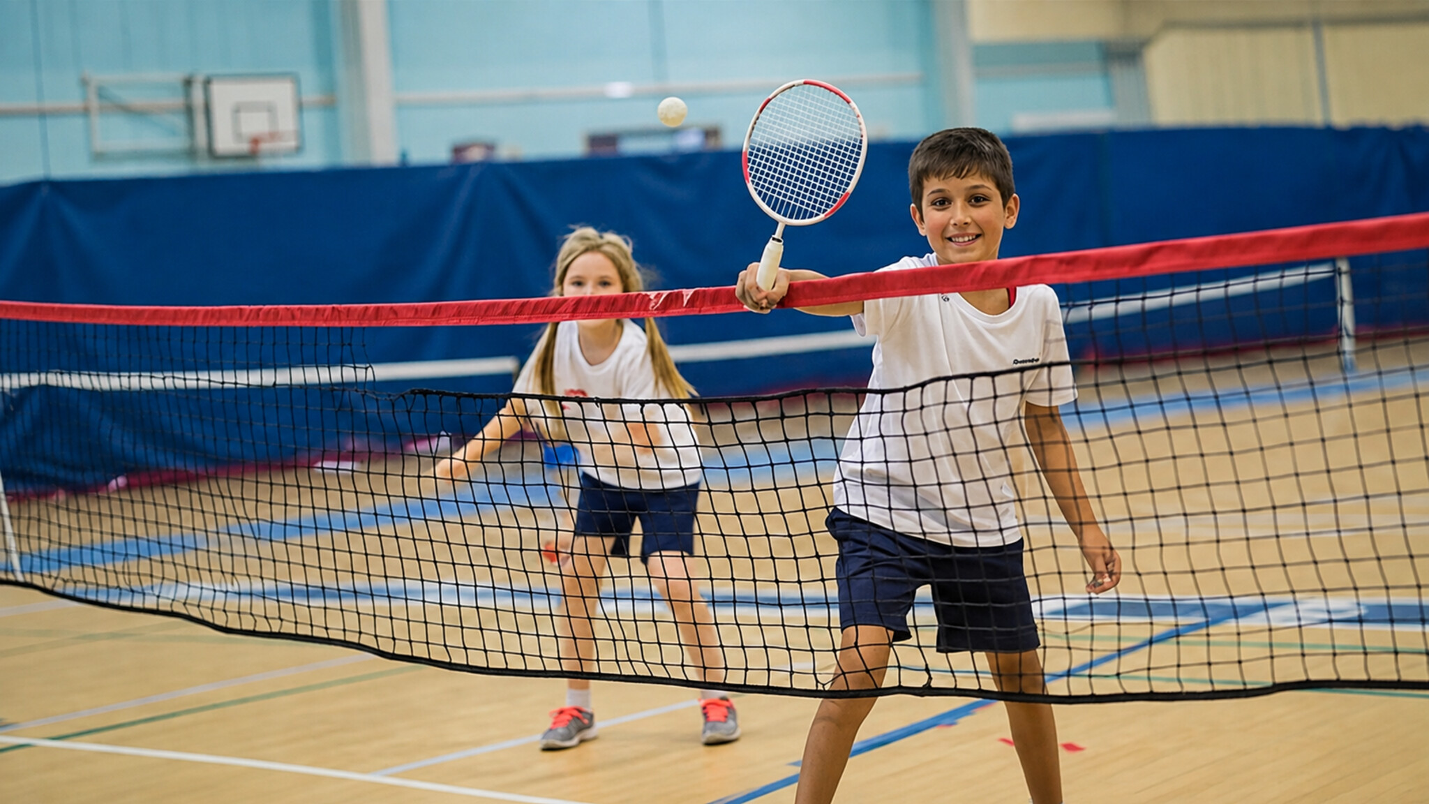 Children playing badminton at an indoor youth academy